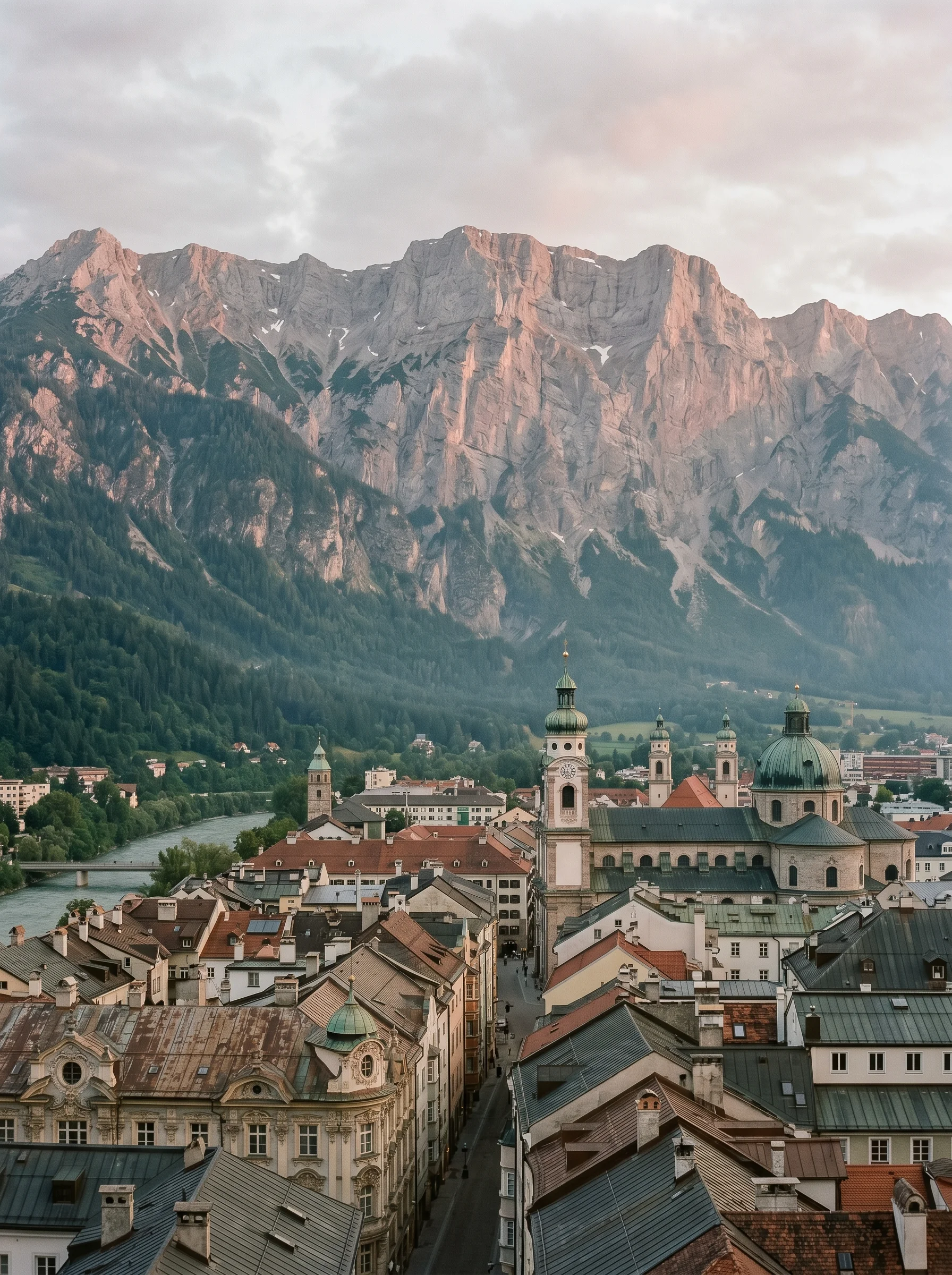 I tetti di Innsbruck sotto la parete verticale di calcare della Nordkette, con un morbido alpenglow sulla montagna.